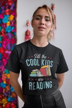 a woman wearing a black t - shirt that says, all the cool kids are reading