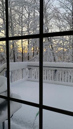 the snow is covering the deck and trees from inside the house, looking out onto the yard