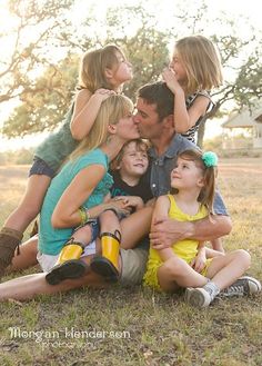 a group of people sitting on top of each other in the middle of a field