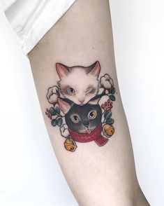 a woman's leg with a cat and flower tattoo on the left side of her arm