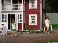 two children walking towards a red house with white balconies on the porchs