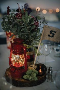 the table is set with a red lantern and flowers in it, along with other decorations