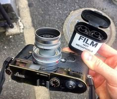 a person holding up a camera with the lens attached to it's body and its case