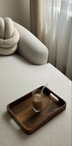 a tray with a drink on it sitting on top of a bed next to a pillow