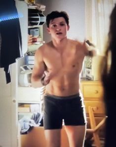 a shirtless young man is standing in front of a mirror