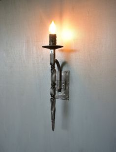 a candle is lit on the wall next to a light fixture that has been turned on