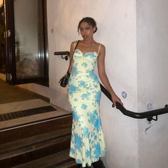 a woman in a yellow and blue dress is standing on the stairs