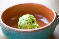 a bowl filled with guacamole sitting on top of a wooden table