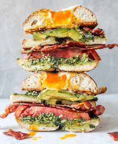 four sandwiches stacked on top of each other with bacon, cheese and avocado