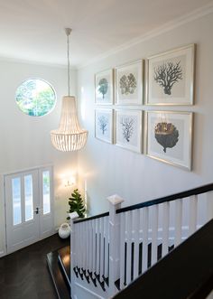 a white staircase with pictures on the wall and a chandelier hanging above it