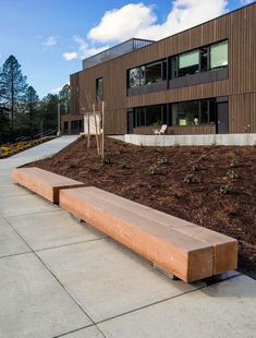 a wooden bench sitting on the side of a road next to a tall brown building