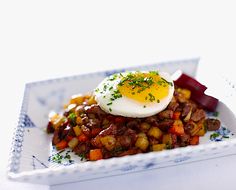 an egg is sitting on top of some food in a blue and white dish with red peppers