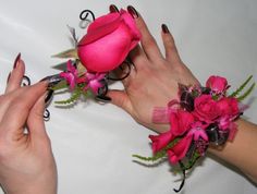 two hands are holding pink flowers and scissors