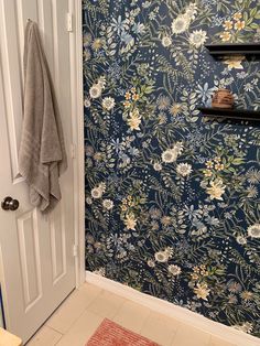 a bathroom with blue floral wallpaper and white door