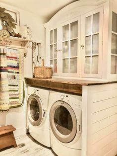 a washer and dryer in a small room with white cupboards on the wall