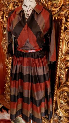 "This gorgeous dress is from the early 50's by Henry Rosenfeld.  Made of a crisp polished cotton.  Rich colors in black, brown and copper. Shirt waist style with button front.  Full pleated skirt.  Dolman sleeve.  The quality and condition are simply beautiful. It comes with a very nice brown narrow leather belt also in beautiful condition.  Best fit would be a Medium, however, please see the measurements below for a proper fit.  All sales are final. Measurements Armpit-armpit doubled 38\" Waist 27\" Hip free Length from nape of neck 45\" Belt 3/4\"x30\"" Retro Fall Dresses For Vintage Events, Retro Dresses For Vintage Events In Fall, Retro Brown Dress For Fall, Retro Formal Dresses For Fall, Brown Vintage Dress For Fall, Fall Vintage Brown Dress, Brown Vintage Evening Dress, Vintage Brown Evening Dress, Nape Of Neck