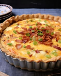 a quiche with bacon and green onions in a pie pan