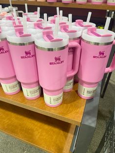 pink coffee mugs with straw sticking out of them sitting on a shelf in a store