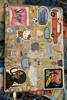 an open notebook covered in stickers on top of a bed