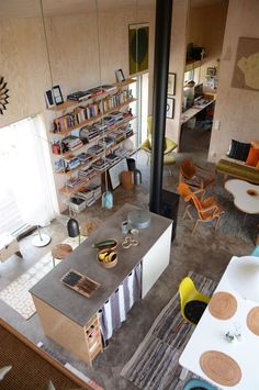 an aerial view of a living room and dining area with chairs, tables, bookshelves and shelves