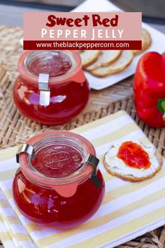 two jars filled with red pepper jelly sitting on top of a table next to crackers