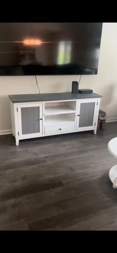 a flat screen tv sitting on top of a white entertainment center in a living room