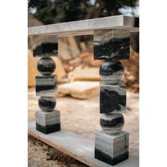 an outdoor sculpture made out of marble blocks and stones on the ground with trees in the background