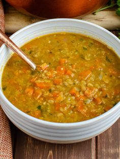 a bowl of soup with carrots and celery in it on a wooden table