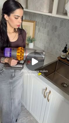 a woman is holding a hair dryer in her hand while standing next to a sink