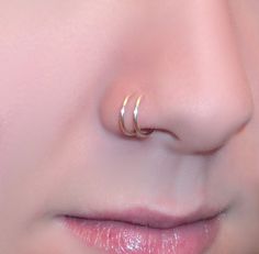 a woman's nose with two gold rings on it