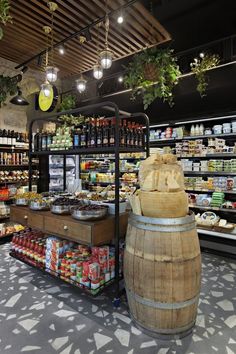 a store filled with lots of different types of food and drinks on display next to a wooden barrel