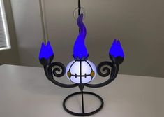 a blue and white chandelier hanging from a metal pole with three lights on it