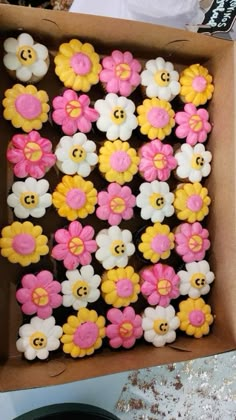 a box filled with lots of decorated cookies in different colors and sizes on top of a table