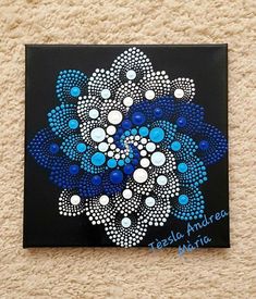 a painting with blue and white dots in the center on a black background, it looks like an abstract flower