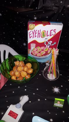 a table topped with bowls filled with food and drinking glasses next to a box of eyeballs