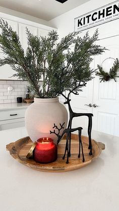 a white kitchen with a candle and deer figurines on a tray in front of it