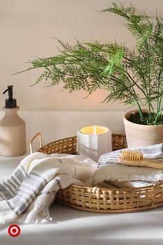 a wicker basket with towels, candles and plants in it sitting on a table