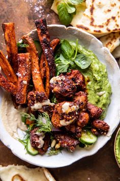 a white bowl filled with food next to pita bread