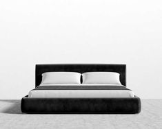 a black and white photo of a bed with two pillows on top of it, in front of a wall