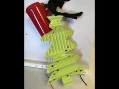 a black cat sitting on top of a green christmas tree next to a red can