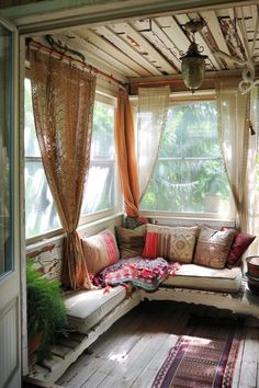 a couch sitting under a window on top of a wooden floor next to a potted plant