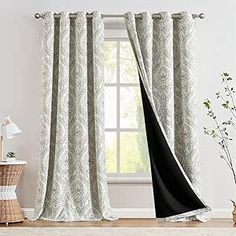 a living room with white walls and curtains on the window sill, next to a vase