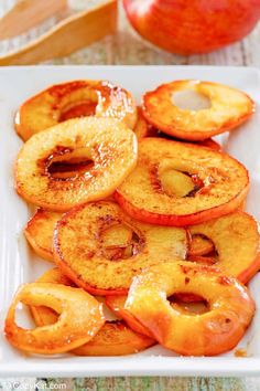 sliced apples on a white plate next to an apple