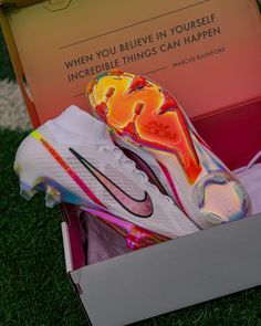 a pair of nike shoes in a box on the grass near a sign that says, when you believe in yourself incredible things can happen