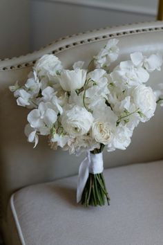 a bouquet of white flowers sitting on top of a couch next to a chair with an arm rest