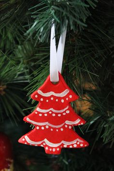 a red christmas tree ornament hanging from a pine tree with white polka dots