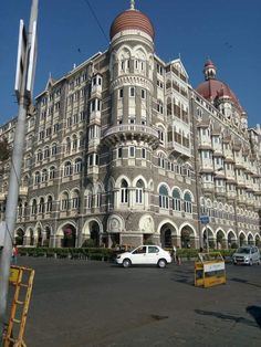 a large building with many windows on the top floor and two cars parked in front of it