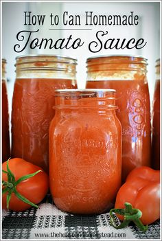 four jars filled with tomato sauce sitting on top of a table next to some tomatoes