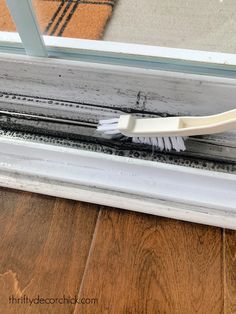 a white brush sitting on top of a window sill next to a wooden floor