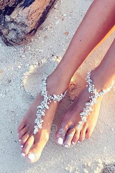 someone is wearing white beaded barefoot sandals on the beach